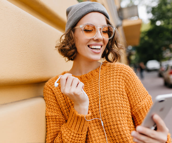 photo of a girl in headphones holding a phone in her hands